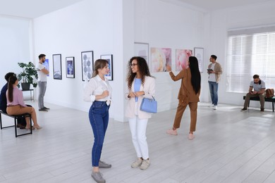 Photo of People viewing exposition in modern art gallery