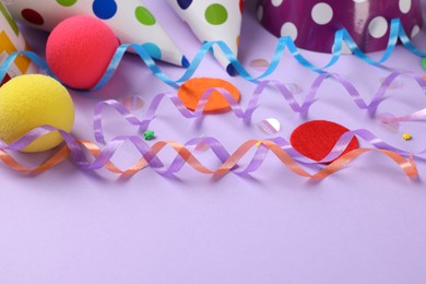 Photo of Colorful serpentine streamers and other party accessories on violet background, closeup