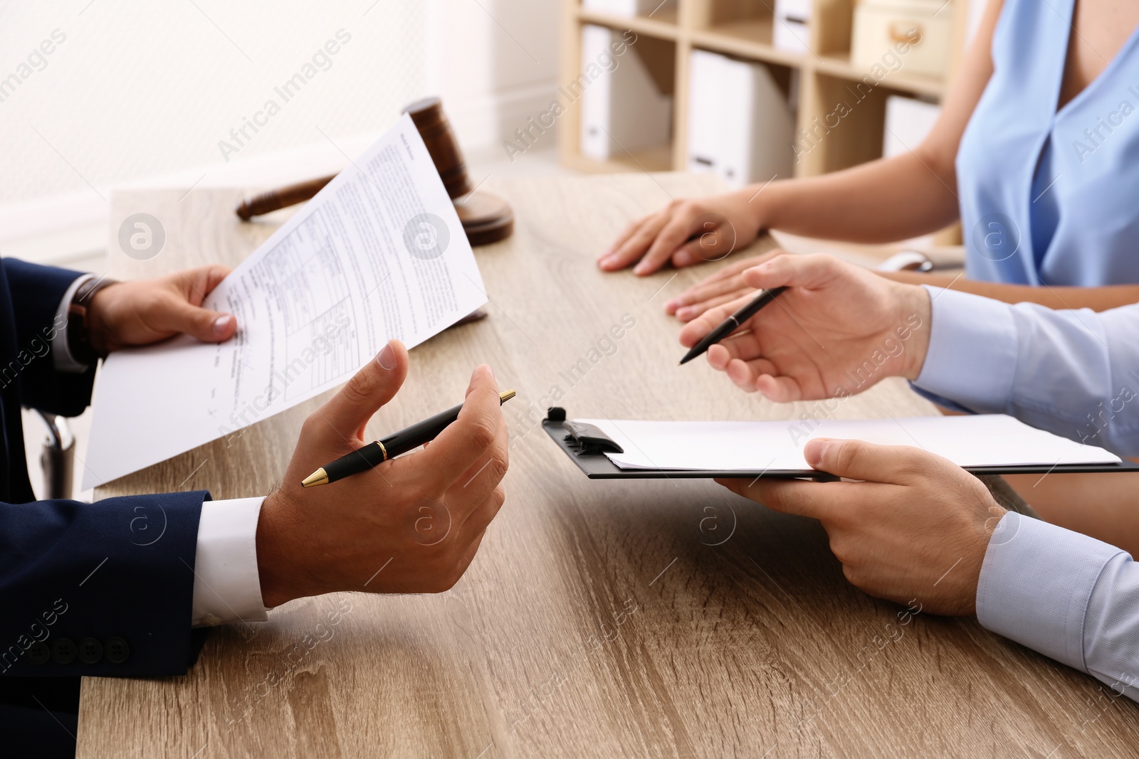 Photo of Lawyer working with clients at table in office, focus on hands