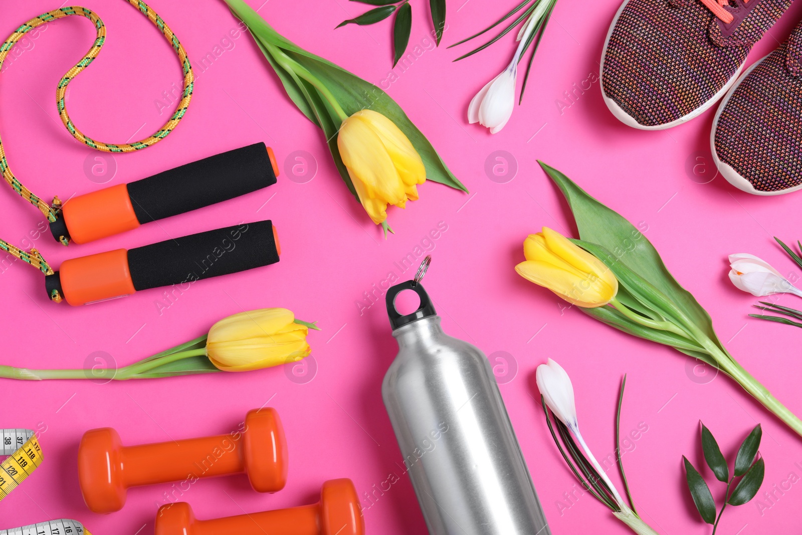 Photo of Flat lay composition with spring flowers and sports items on pink background