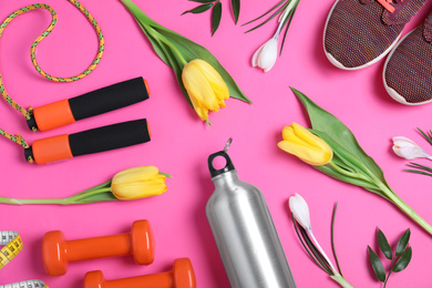 Photo of Flat lay composition with spring flowers and sports items on pink background