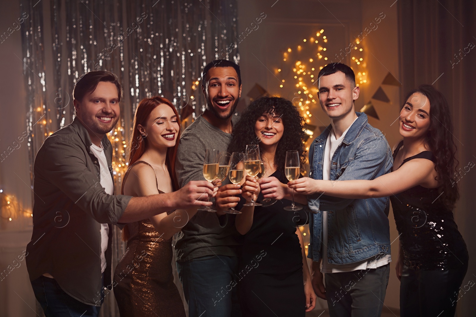 Photo of Happy friends with glasses of sparkling wine celebrating birthday indoors