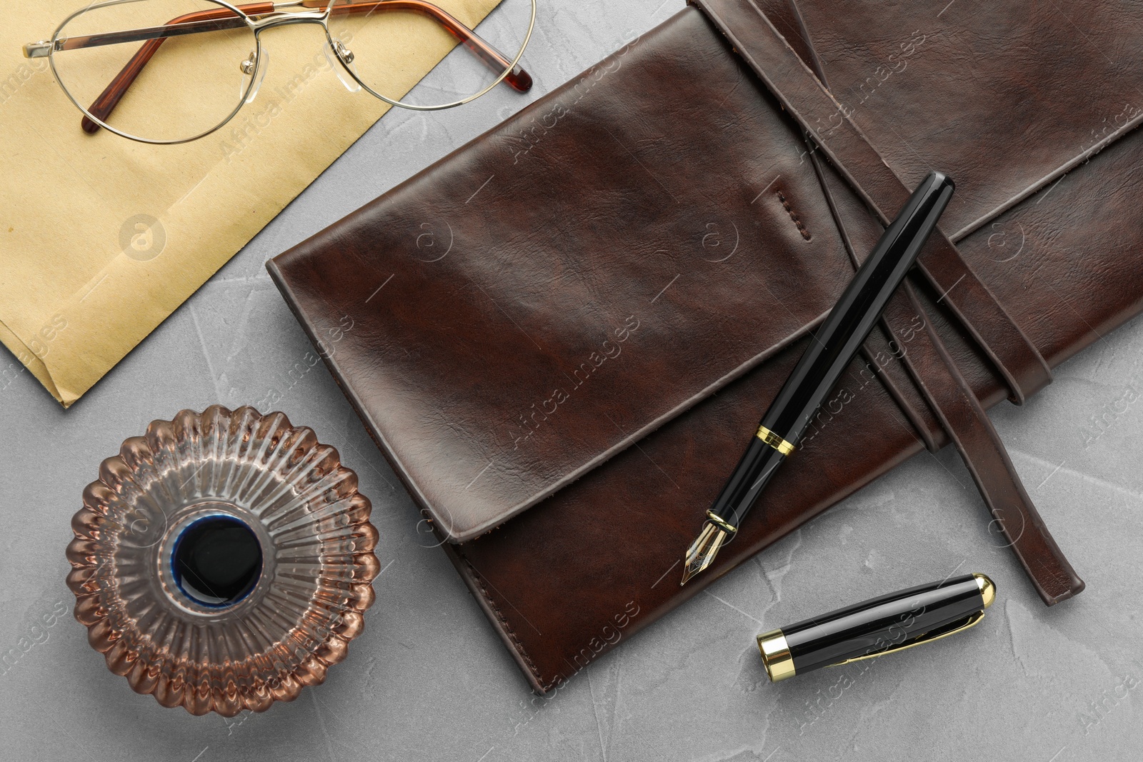 Photo of Flat lay composition with stylish fountain pen and inkwell on light grey textured table