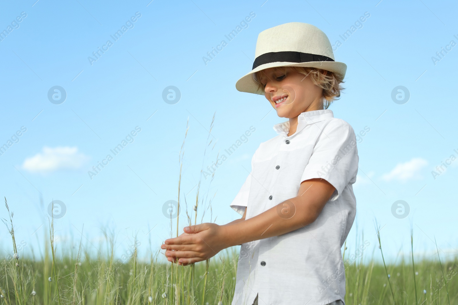 Photo of Cute little boy wearing stylish hat outdoors. Child spending time in nature