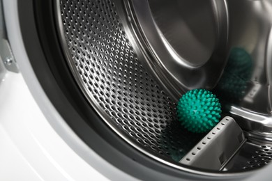 Green dryer ball in washing machine drum, closeup