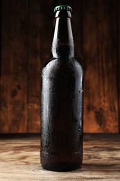 Glass bottle of beer on wooden table