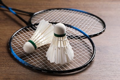 Photo of Feather badminton shuttlecocks and rackets on wooden table, closeup
