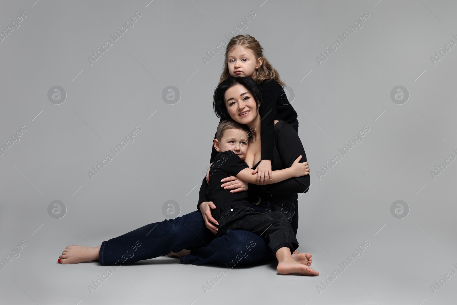 Photo of Little children with their mother on grey background