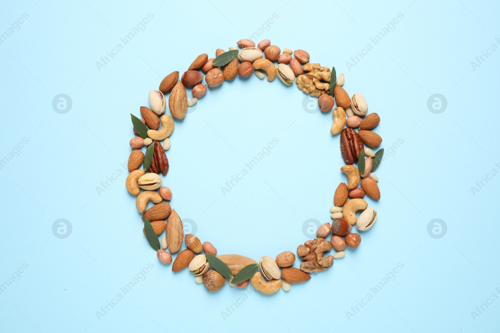 Photo of Different delicious nuts on light blue background, flat lay. Space for text