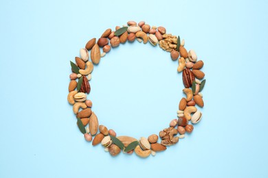 Photo of Different delicious nuts on light blue background, flat lay. Space for text