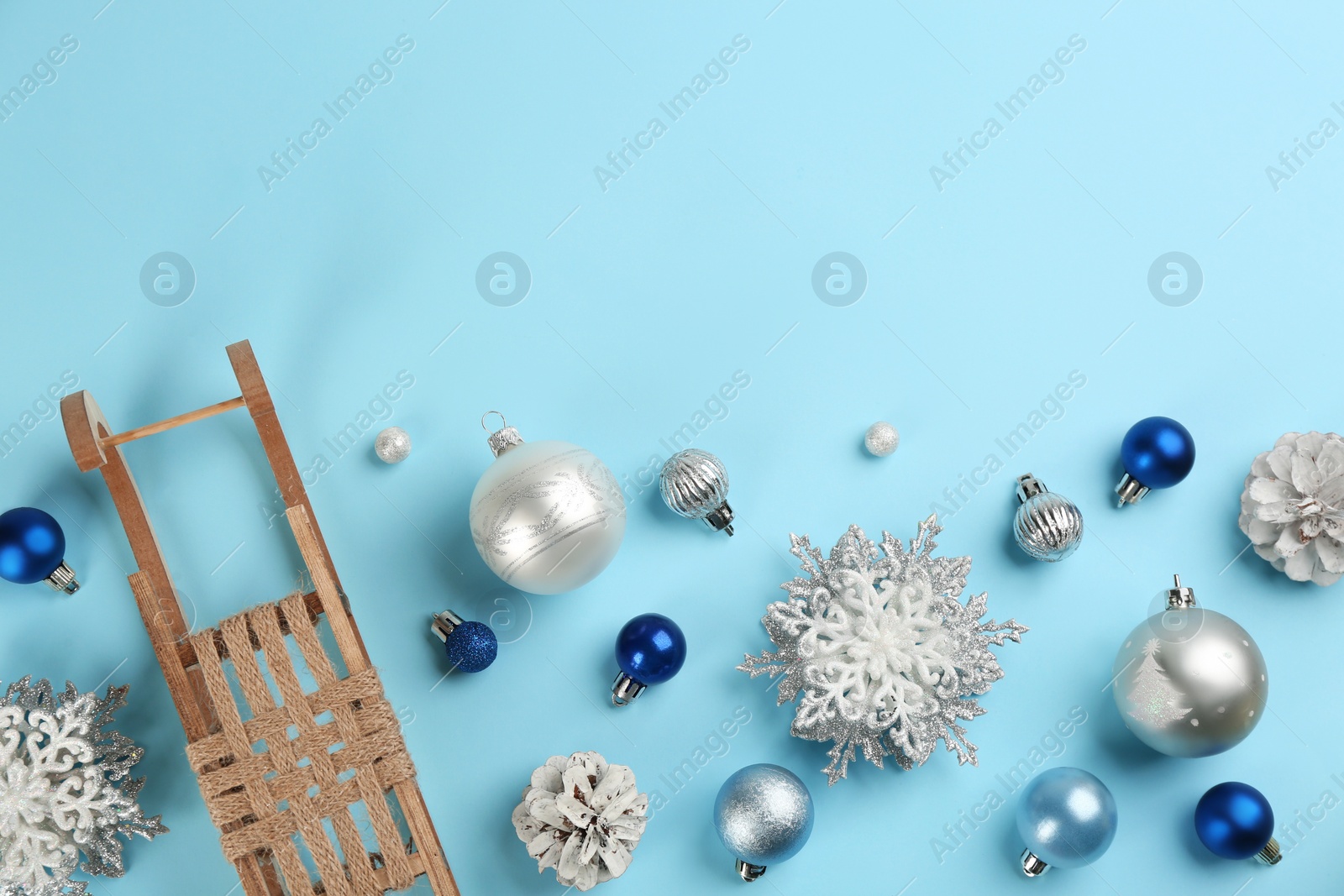 Photo of Beautiful Christmas composition with miniature sleigh on light blue background, flat lay. Space for text