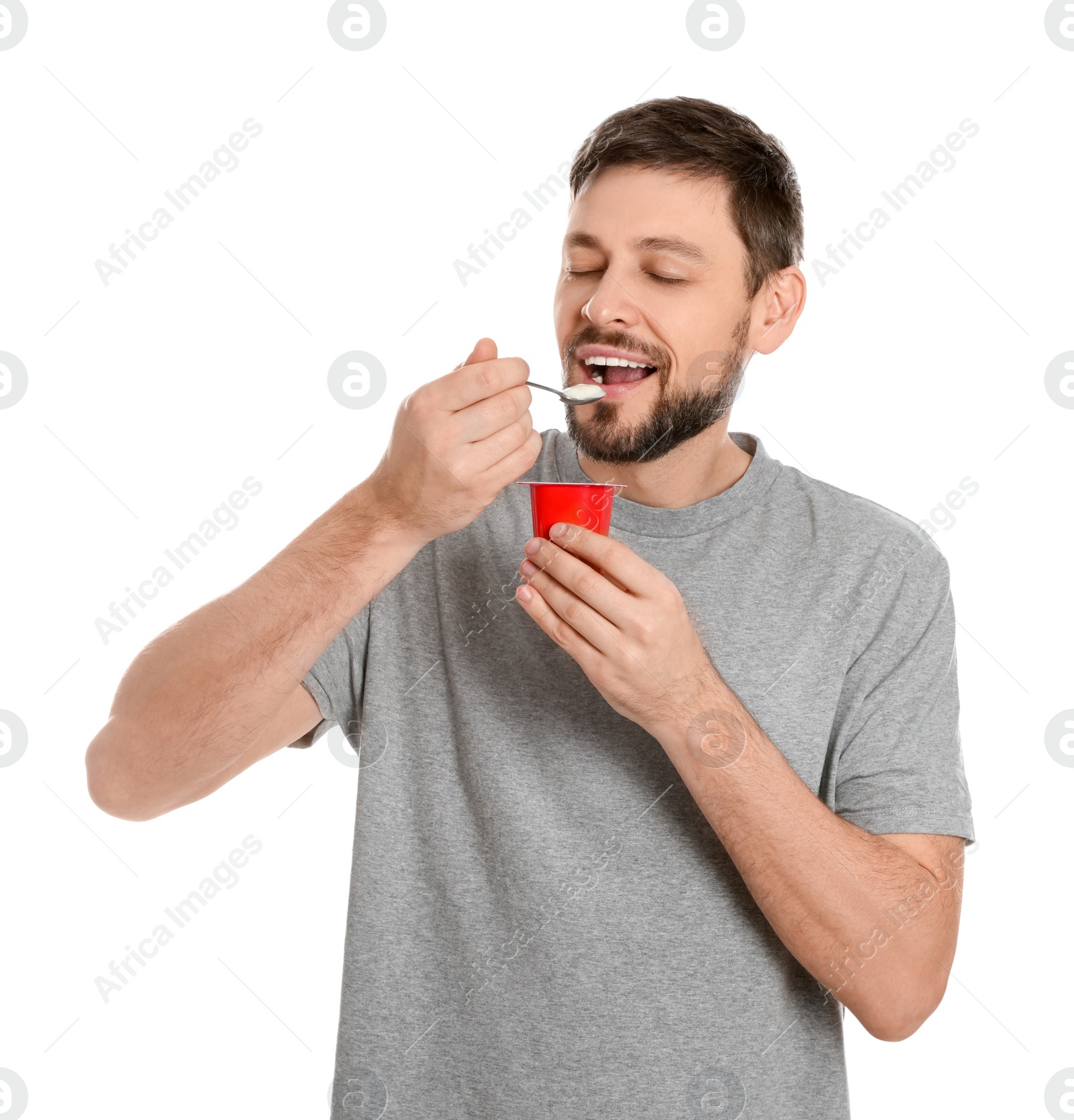 Photo of Handsome man eating tasty yogurt on white background
