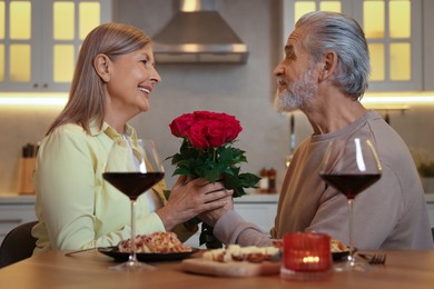 Photo of Affectionate senior couple having romantic dinner at home