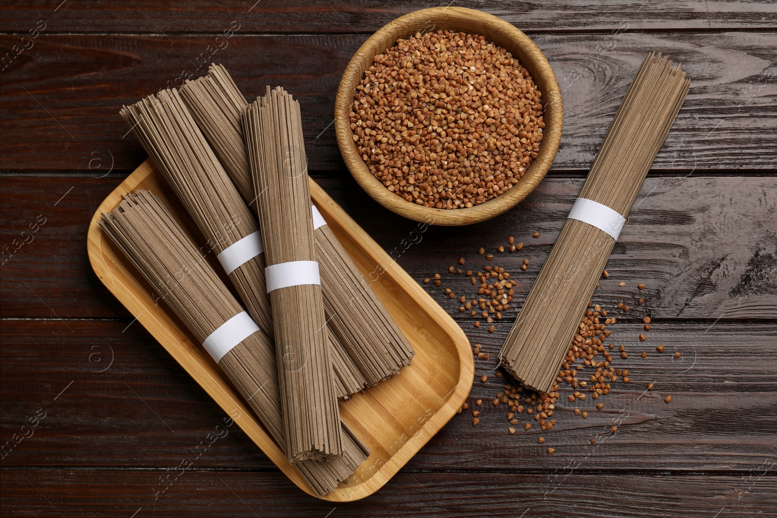 Photo of Uncooked buckwheat noodles (soba) and grains on wooden table, flat lay