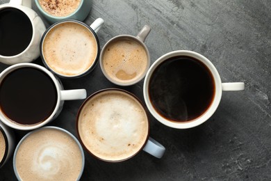 Photo of Many cups of different coffees on slate table, flat lay