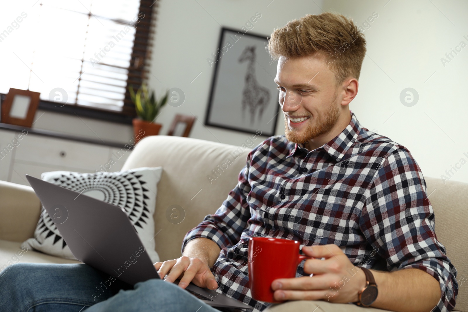 Photo of Young man using laptop in living room