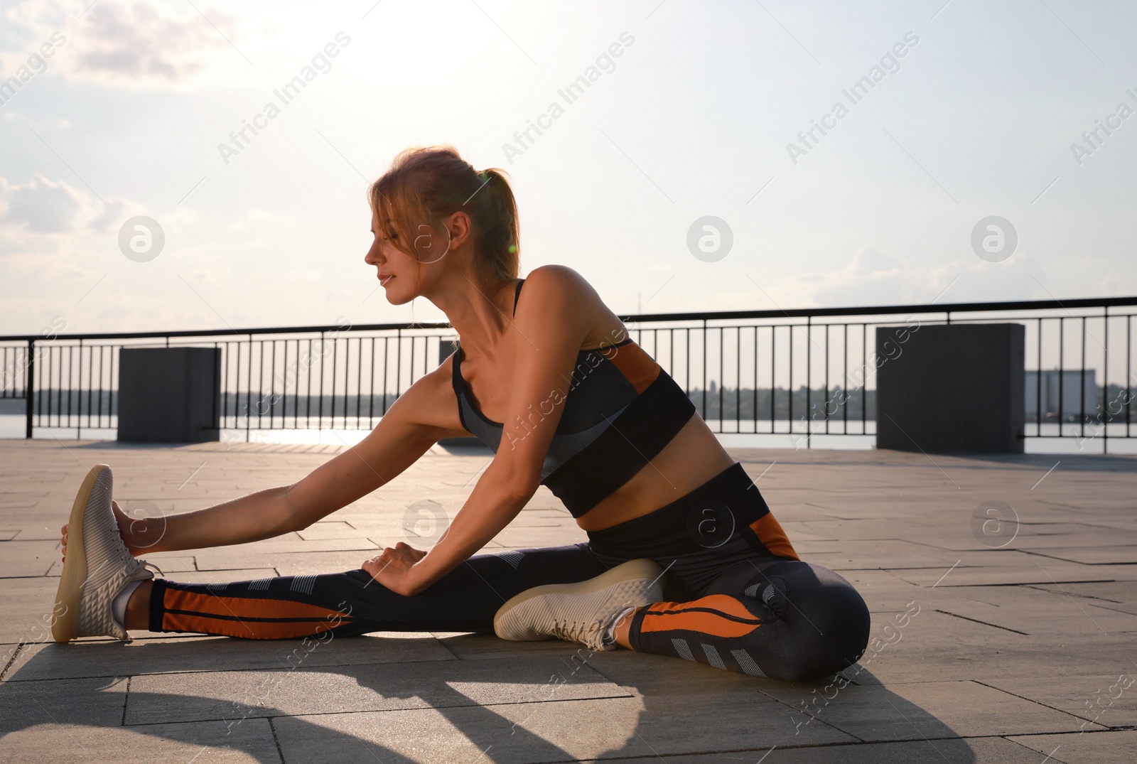 Photo of Beautiful woman in sportswear doing exercises outdoors on sunny day