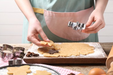 Photo of Woman making Christmas cookies with cutters at wooden table, closeup