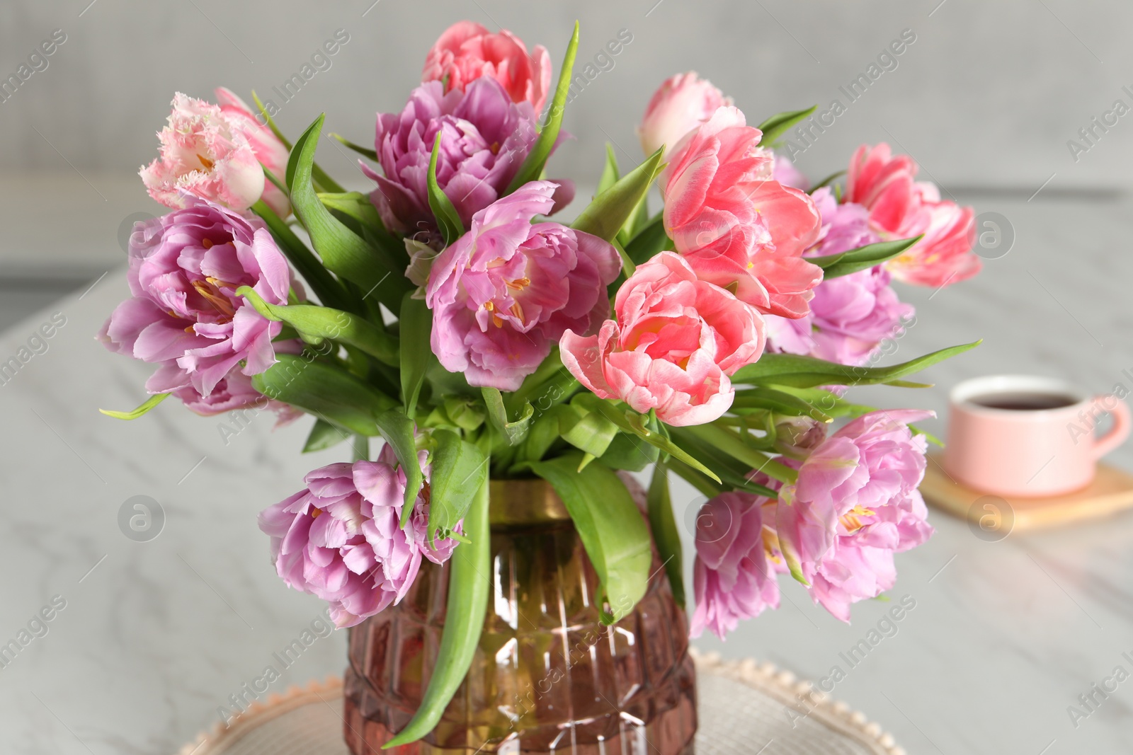 Photo of Beautiful bouquet of colorful tulip flowers on white marble table, closeup