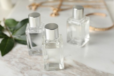 Photo of Bottles of essential oil on white marble table, closeup