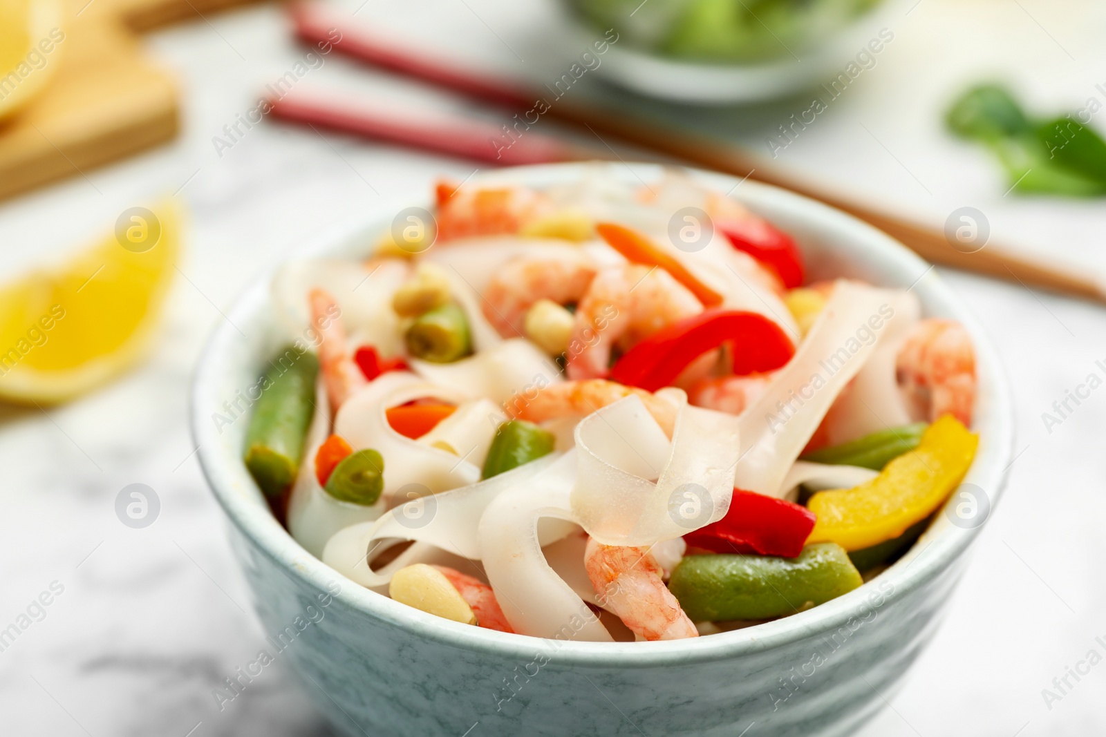 Photo of Tasty cooked rice noodles with shrimps and vegetables in bowl, closeup