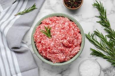 Photo of Bowl of raw fresh minced meat with rosemary and spices on white marble table, flat lay