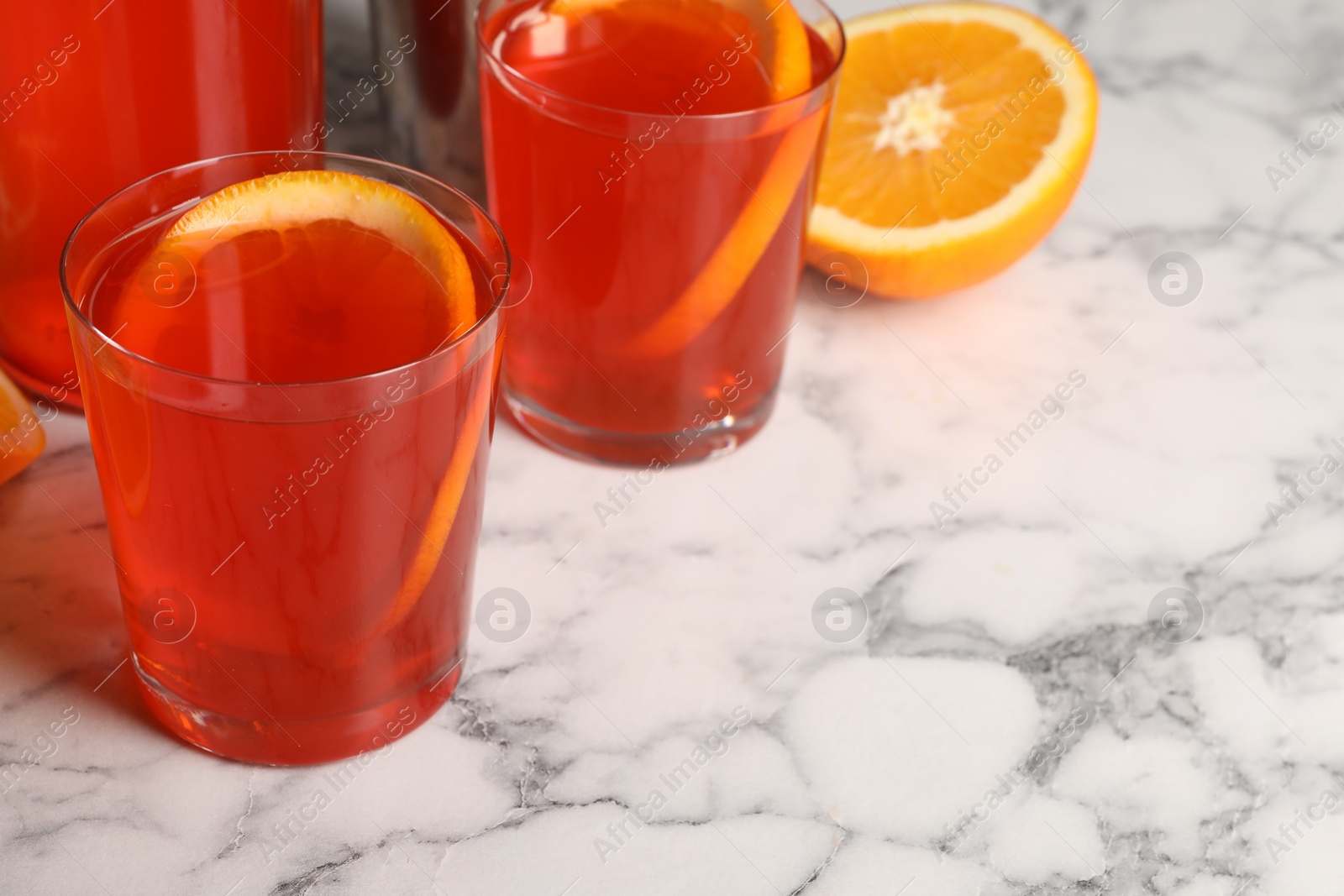 Photo of Aperol spritz cocktail and orange slices in glasses on white marble table, closeup. Space for text