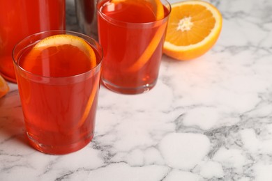 Aperol spritz cocktail and orange slices in glasses on white marble table, closeup. Space for text