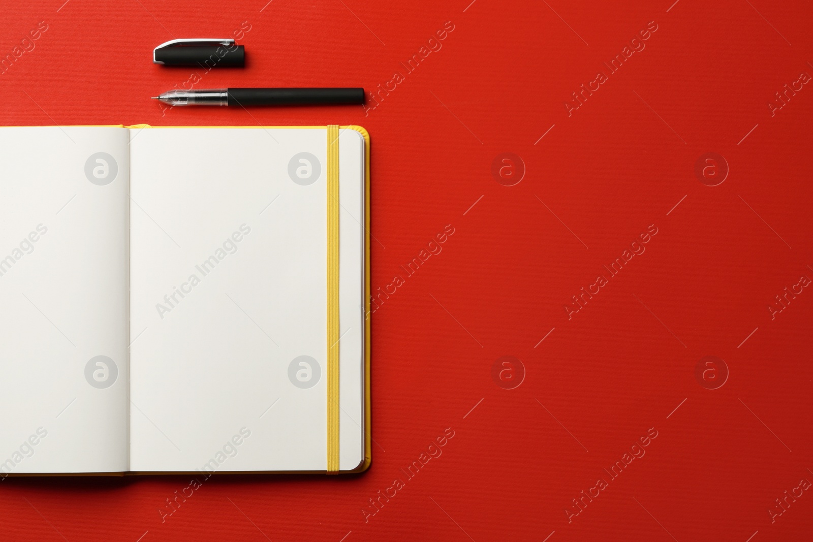 Photo of Notebook and pen on red background, flat lay. Space for text