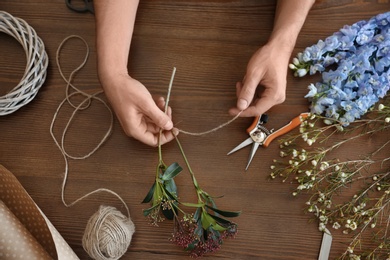 Male florist creating beautiful bouquet at table, closeup