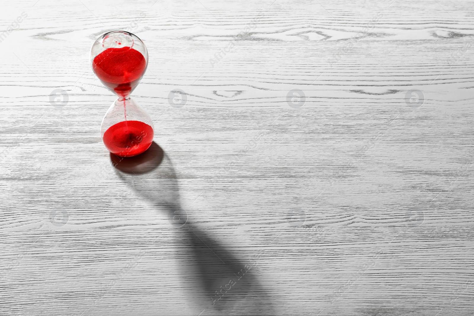 Photo of Hourglass with flowing red sand on wooden background. Time management