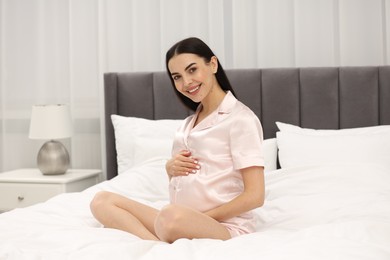 Happy pregnant woman on bed at home