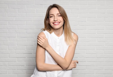 Photo of Portrait of young woman with beautiful face near white brick wall