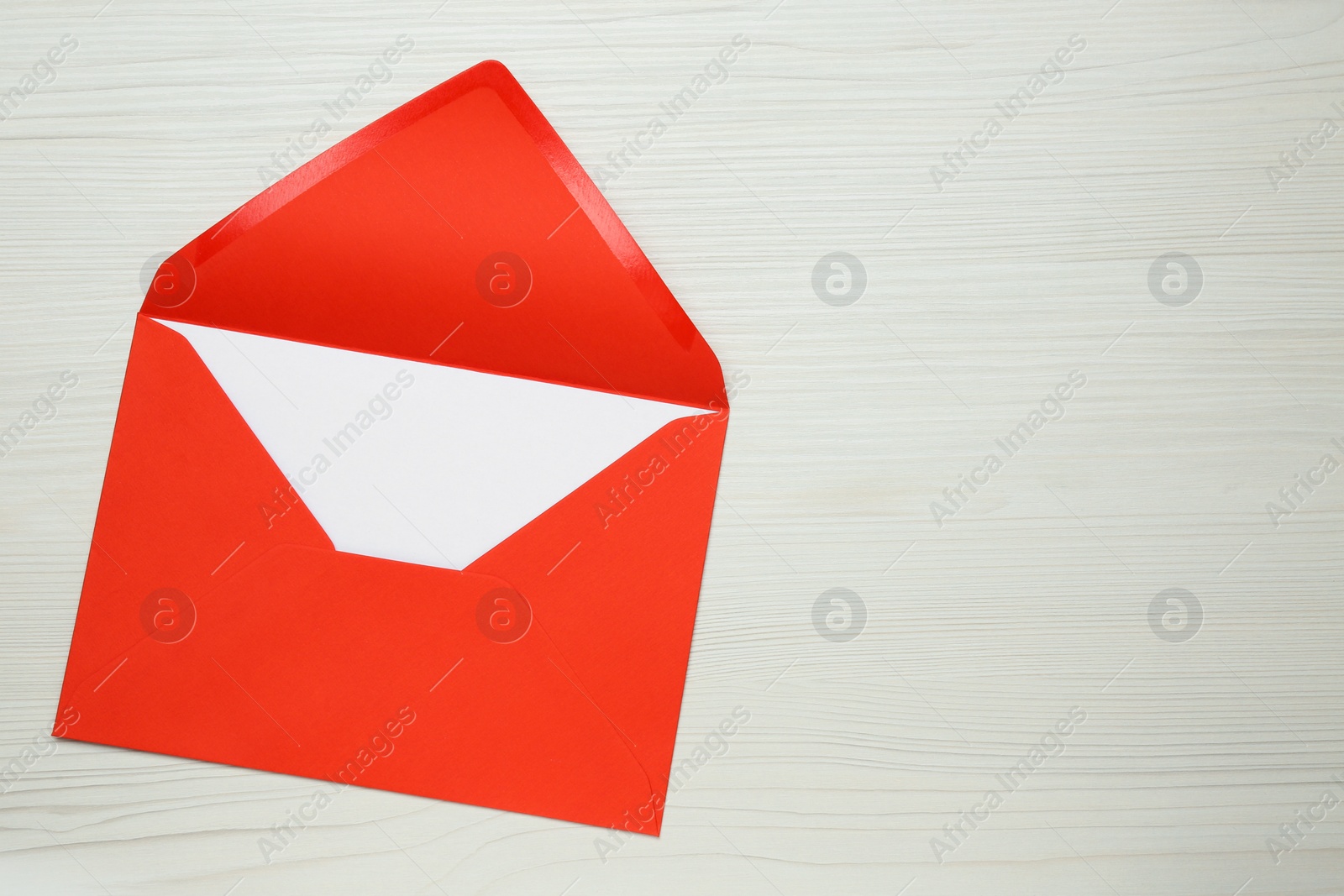 Photo of Envelope with blank paper card on white wooden table, top view. Space for text