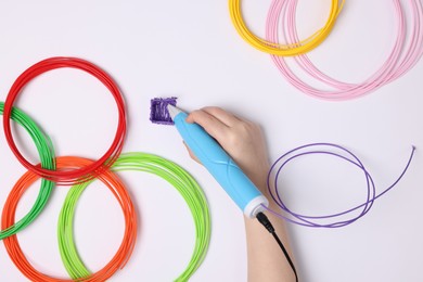 Boy drawing with stylish 3D pen on white background, top view