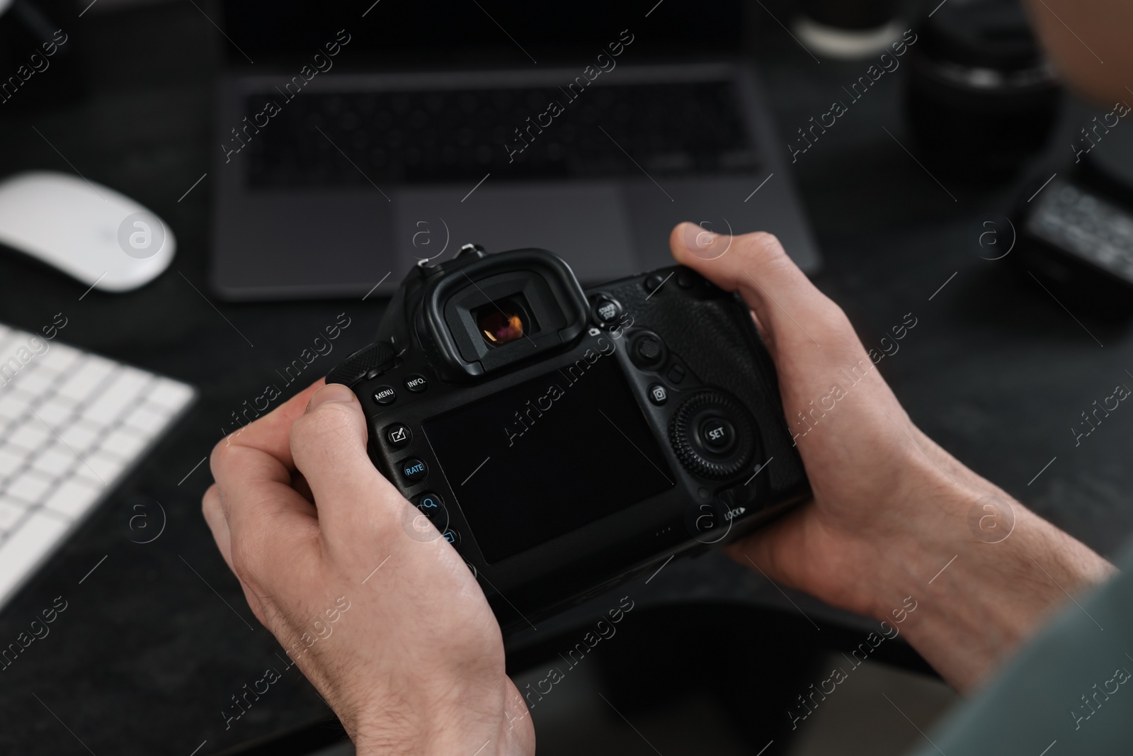 Photo of Photographer holding camera near dark table, closeup