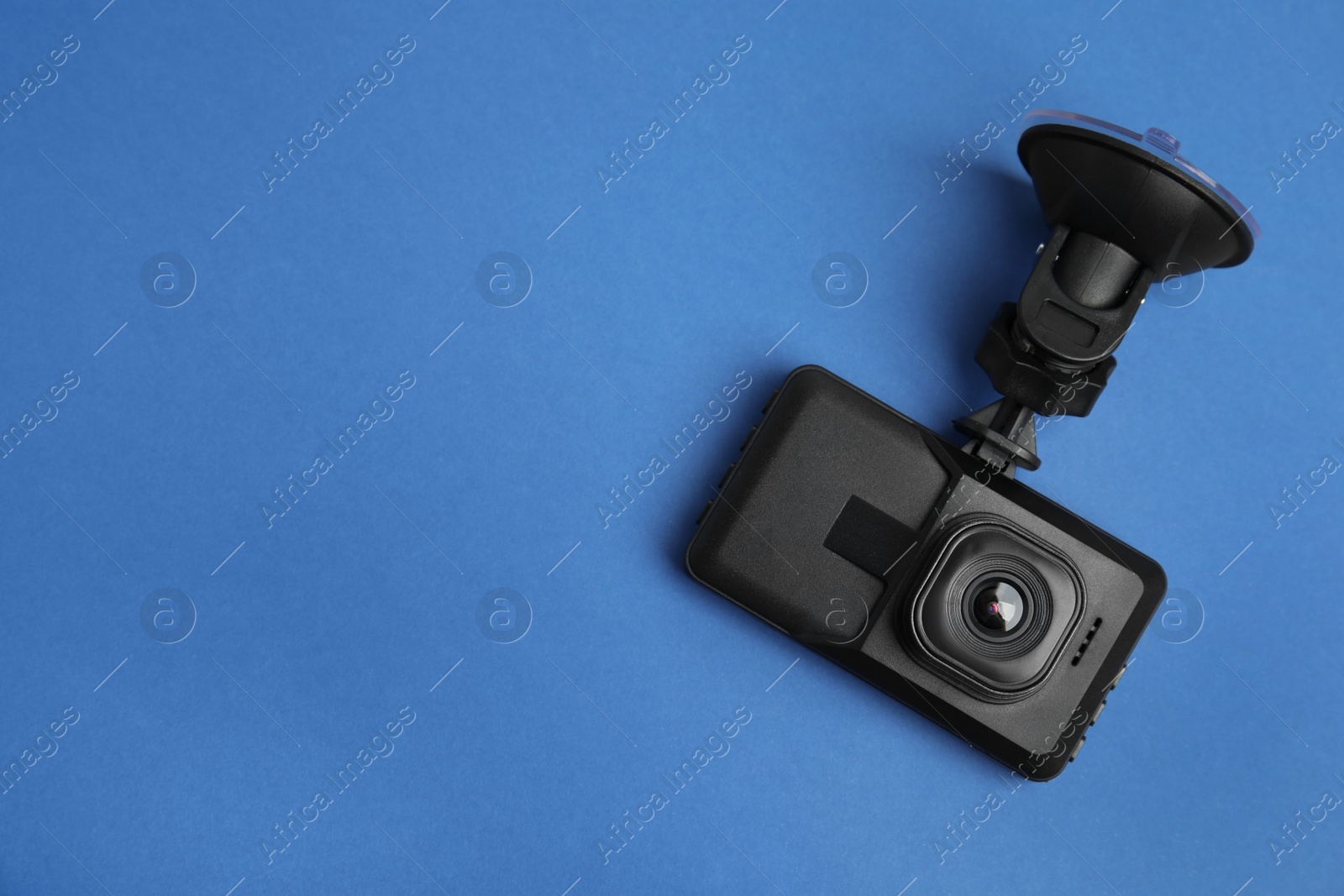 Photo of Modern car dashboard camera with suction mount on blue background, top view. Space for text