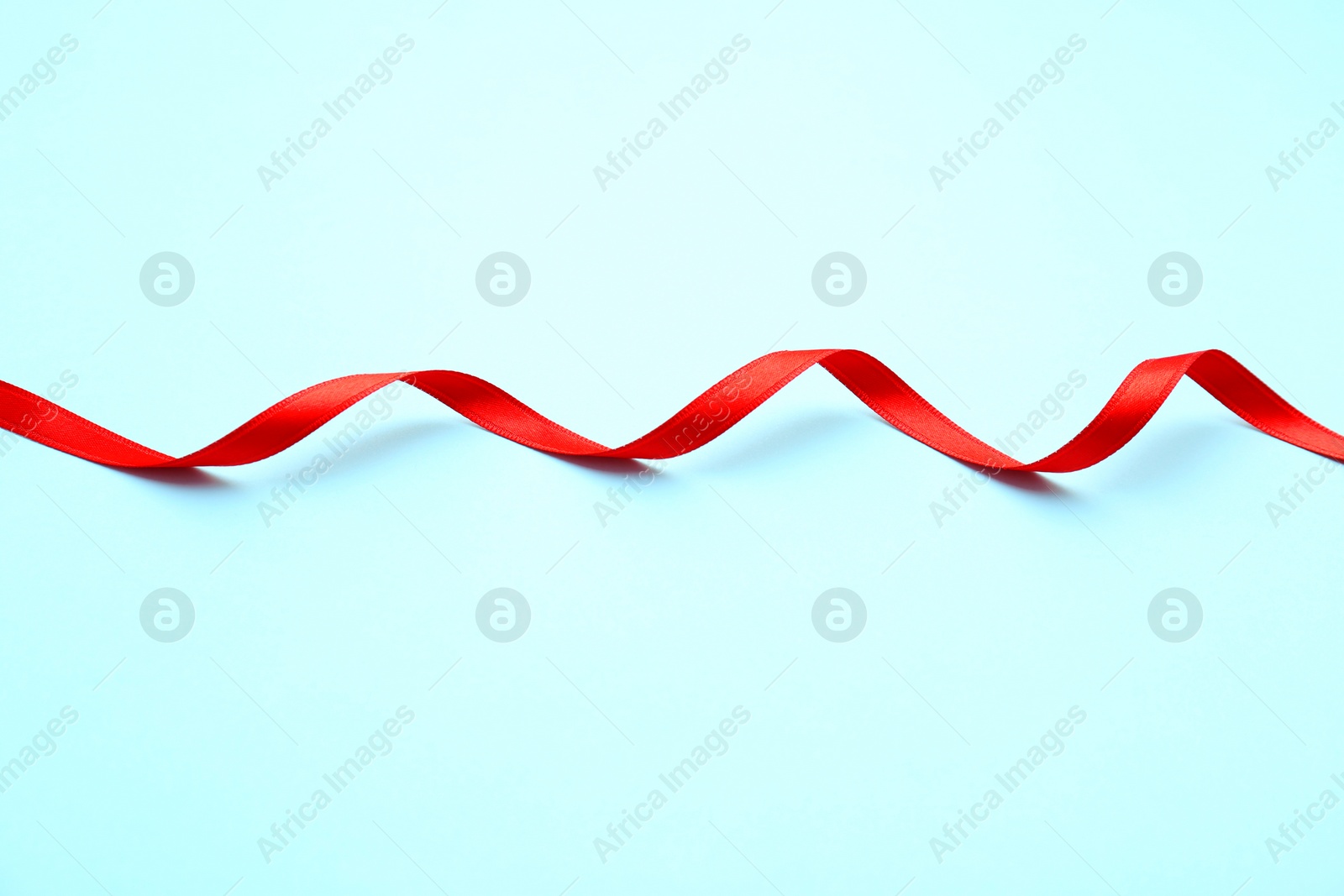 Photo of Simple red ribbon on color background. Festive decoration