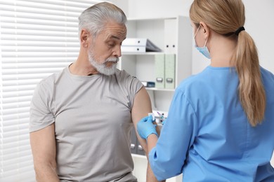 Doctor giving hepatitis vaccine to patient in clinic