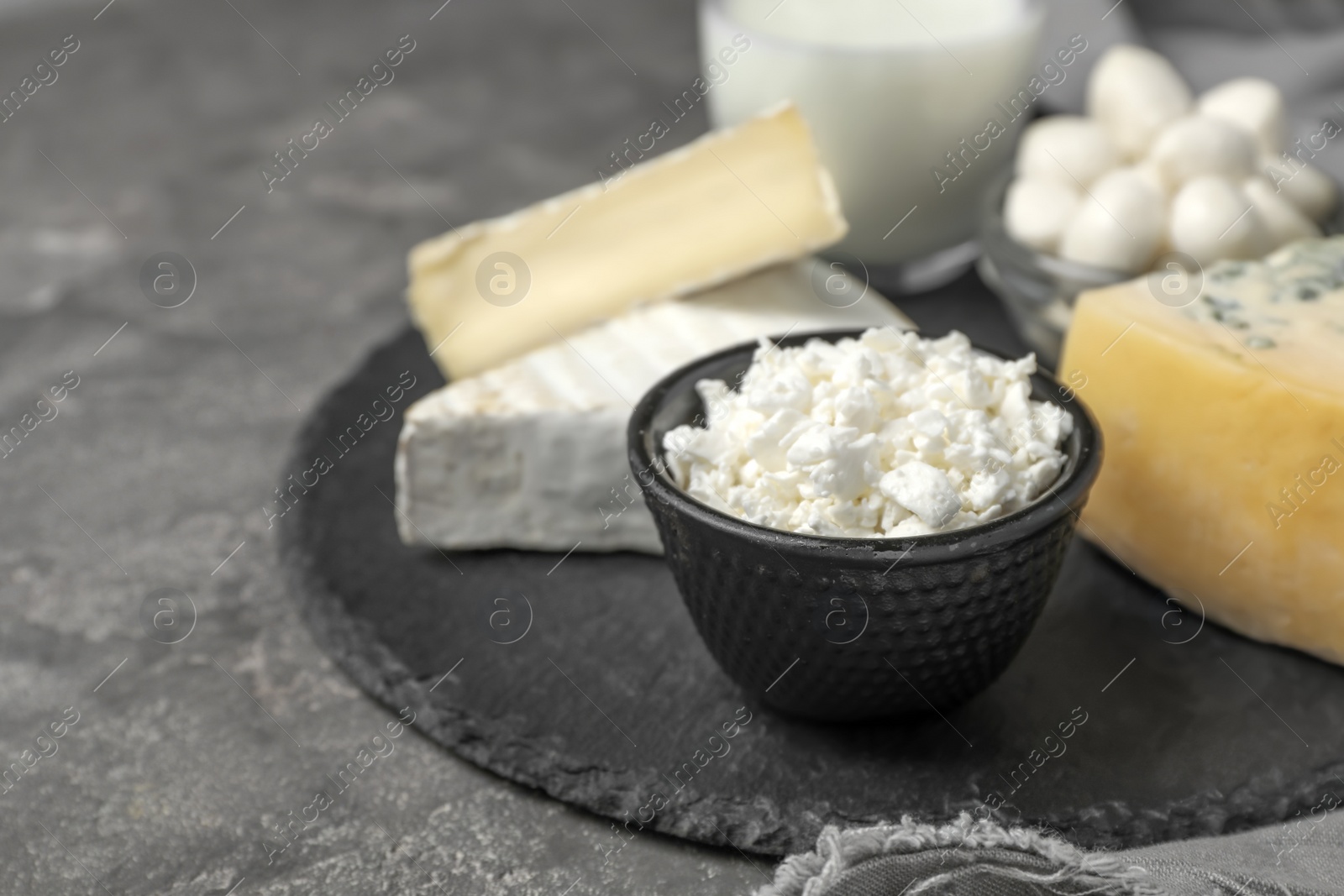 Photo of Bowl with fresh cottage cheese on slate plate. Dairy products
