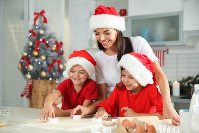 Happy family with Santa hats cooking in kitchen. Christmas time