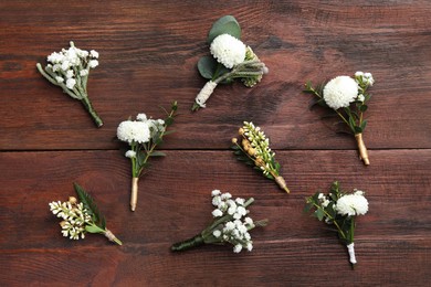 Photo of Small stylish boutonnieres on wooden table, flat lay