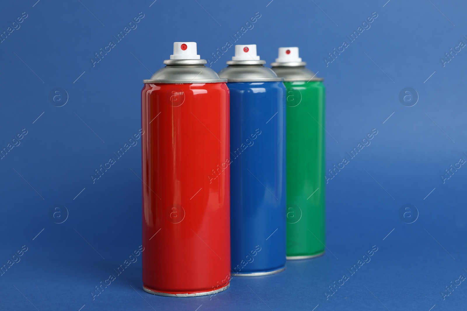 Photo of Colorful cans of spray paints on blue background