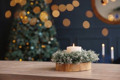 Beautiful burning candle with Christmas decor on wooden table, space for text