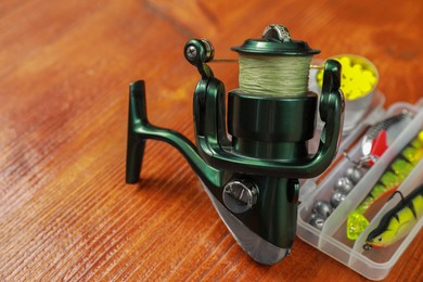 Photo of Fishing tackle. Spinning reel, lures and bait on wooden table, closeup. Space for text