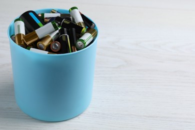 Image of Used batteries in bucket on white table, space for text