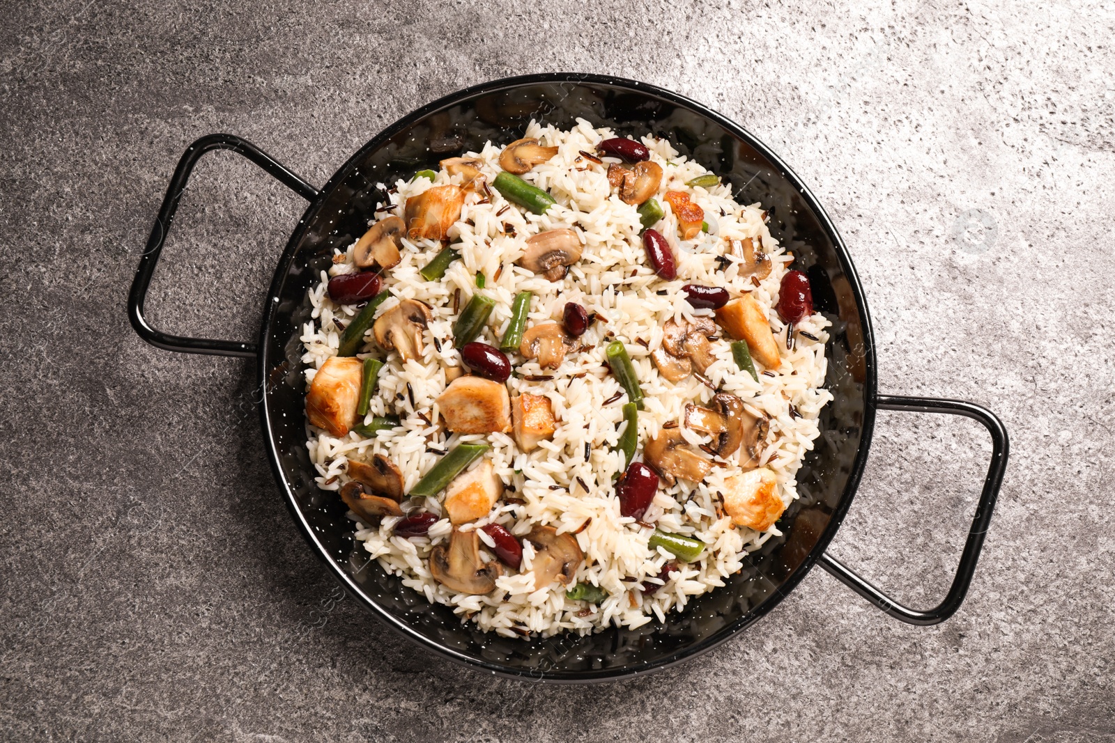 Photo of Delicious rice pilaf with chicken and vegetables on grey table, top view
