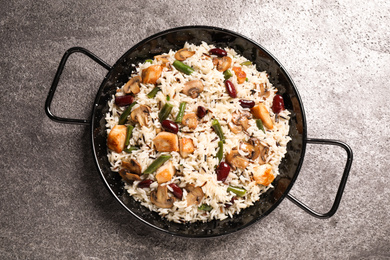 Delicious rice pilaf with chicken and vegetables on grey table, top view