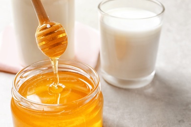 Honey pouring from dipper into jar on table