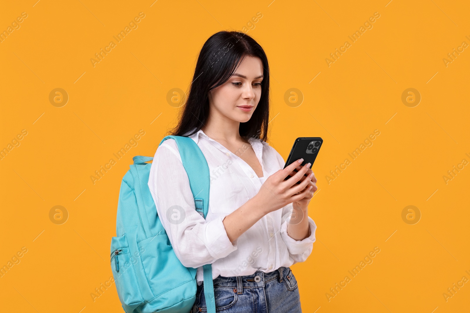 Photo of Student with smartphone and backpack on yellow background